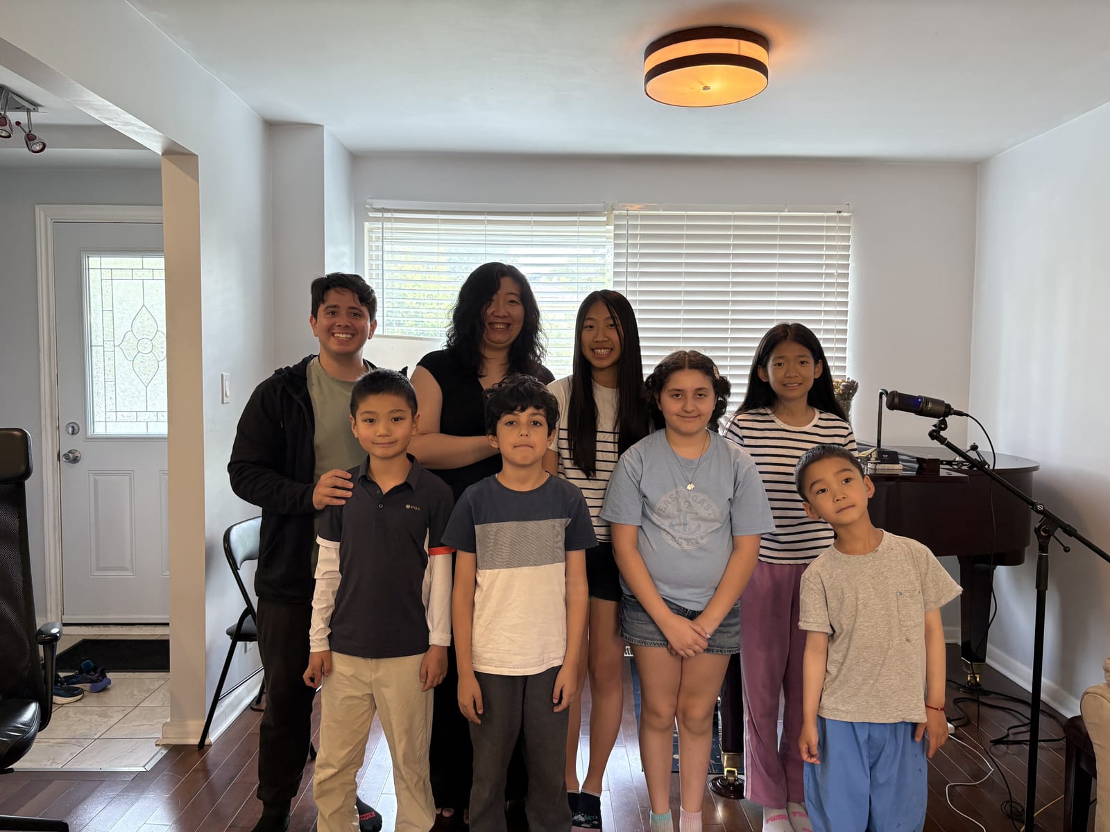 Shuman Zhou and Carlos Fernandez with six students after a monthly studio class, standing beside the grand piano in the studio